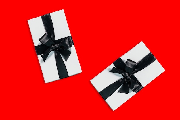 Vista superior de dos cajas de regalo con una cinta sobre fondo rojo con espacio de copia