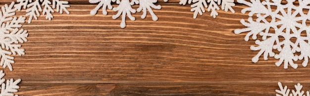 Foto vista superior dos flocos de neve de inverno no banner de fundo de madeira