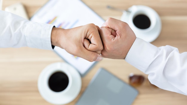 Vista superior de dos hombres tocan las manos de los nudillos. El empresario golpea la mano con el puño después de una reunión de éxito.