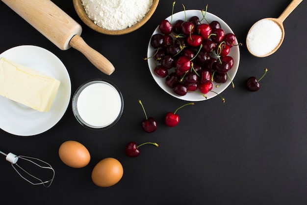 Vista superior dos ingredientes para fazer torta de cereja ou bolo no fundo preto Copie o espaço