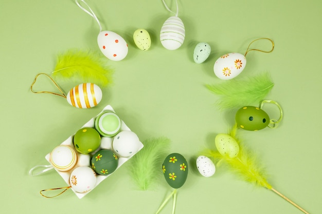 Vista superior dos ovos de Páscoa em um suporte de ovo pintado com diferentes padrões e penas em um fundo verde Copiar espaço Lugar para uma inscrição