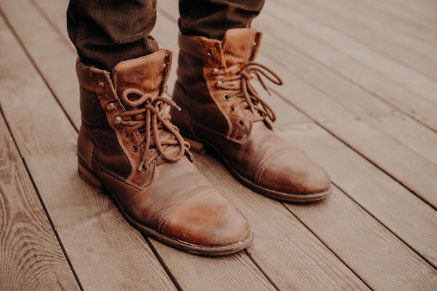 Vista superior dos sapatos do homem no piso ou superfície de madeira Calçado antigo Homem irreconhecível Botas marrons desgrenhadas de couro com atacadores