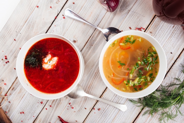 Vista superior de dos sopas de borsch y vegetales en la mesa de madera clara