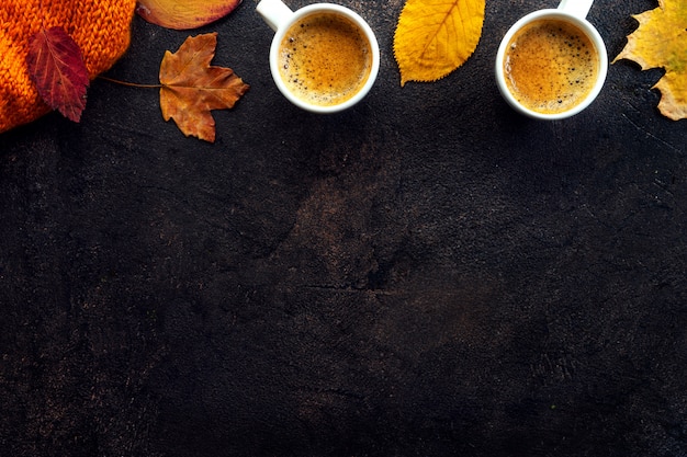 Vista superior de dos tazas de café alrededor de hojas amarillas