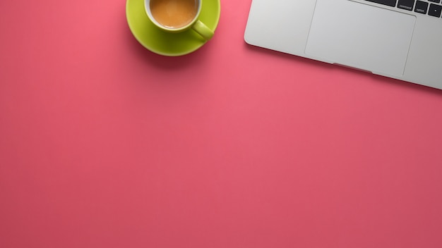 Vista superior del elegante espacio de trabajo con laptop y espacio de copia en el fondo de la tabla rosa