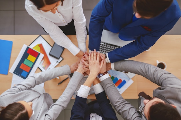 Foto vista superior de empresarios apilando las manos sobre el escritorio. en documentos de escritorio, computadoras portátiles y teléfonos inteligentes. el conocimiento es estar al tanto de lo que puede hacer. la sabiduría es saber cuándo no hacerlo.