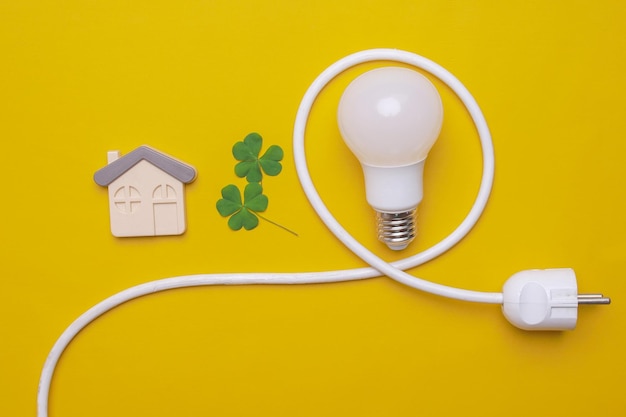 Foto la vista superior del enchufe eléctrico de la bombilla led deja una composición de símbolo de la casa sobre fondo amarillo