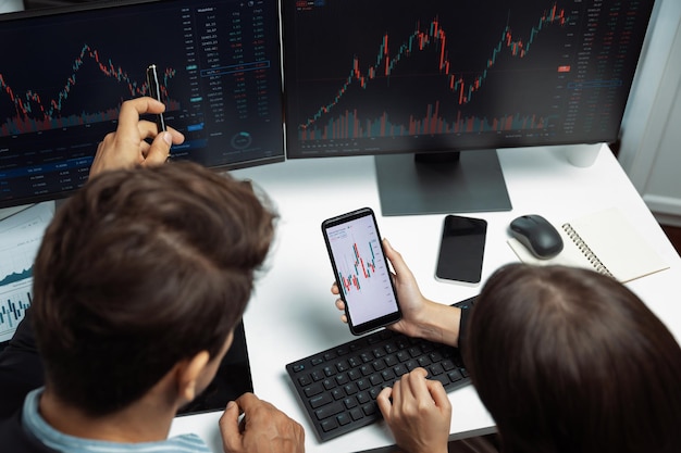 Foto vista superior enfocando el teléfono discutiendo la bolsa de valores dos comerciantes de negocios postulan