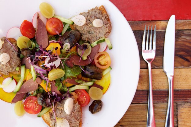 Vista superior de una ensalada fresca en un plato con pan tostado y paté de carne