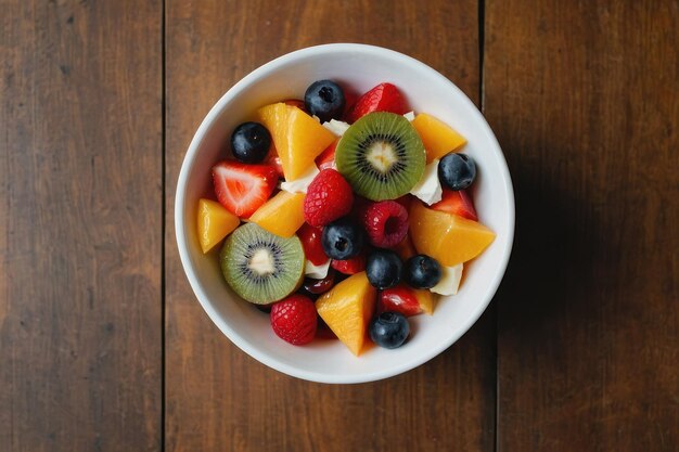 vista superior ensalada de frutas en un cuenco blanco en la mesa marrón