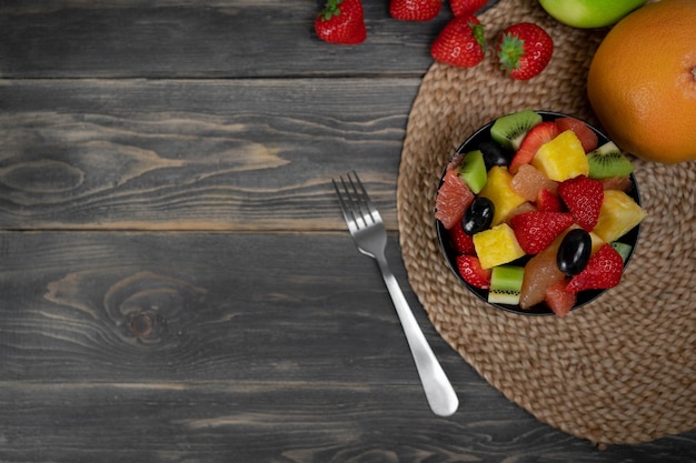 Vista superior de ensalada de frutas frescas en un tazón sobre fondo de madera concepto de comida vegetariana BIO frutas