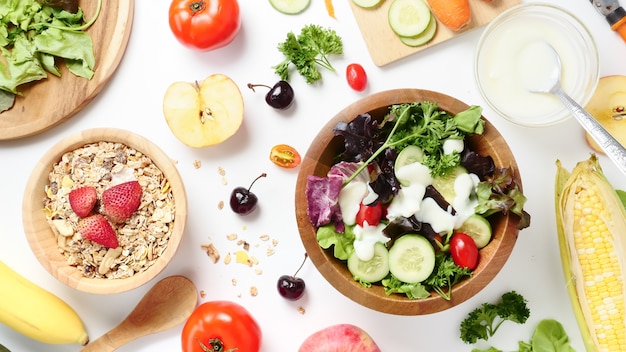 Vista superior de la ensalada de verduras mixtas, muesli y frutas frescas sobre fondo blanco