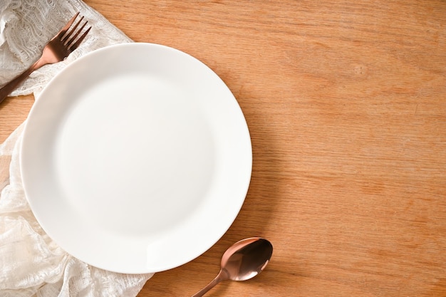 Vista superior del entorno de comedor de tableta simple con cubiertos de plato blanco