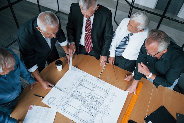 Vista superior del equipo de ancianos empresarios arquitectos tienen una reunión en la oficina y trabaja con el plan.