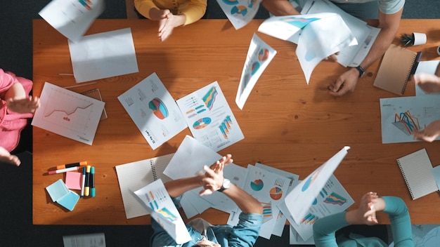 Vista superior del equipo de negocios inteligentes sosteniendo y arrojando papel en el aire Simposio