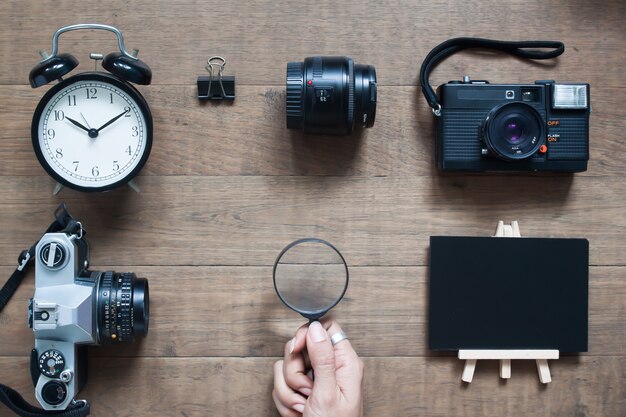 Foto vista superior del escritorio del fotógrafo con la mano de la mujer que sostiene la lupa