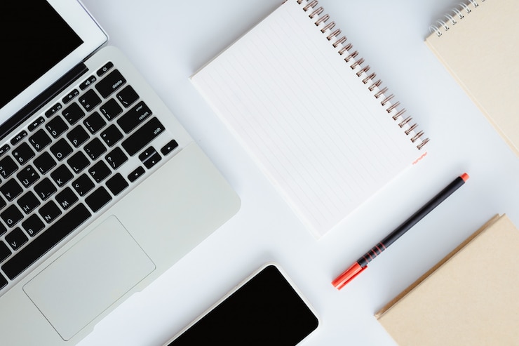 Foto vista superior del escritorio de oficina blanco con computadora portátil, teléfono inteligente, cuaderno y un bolígrafo para negocios y concepto de espacio de trabajo
