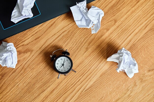 Vista superior del escritorio de oficina de madera con reloj, cuaderno, bolas de papel arrugadas, cambio de mentalidad, plan B, tiempo para establecer nuevos objetivos, planes, concepto de gestión del tiempo, endecha plana.