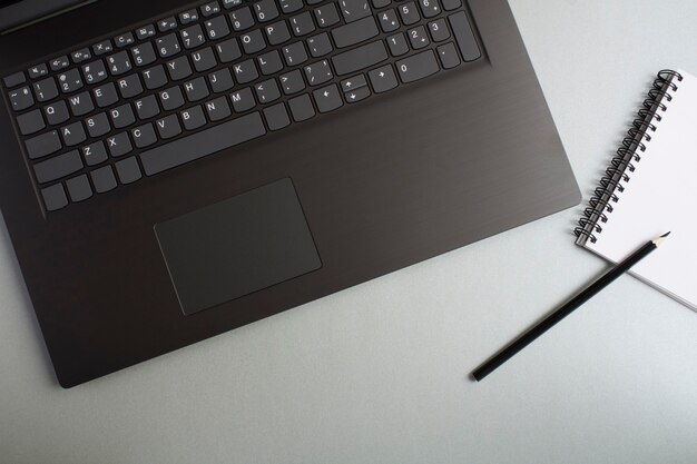 Vista superior del escritorio de oficina con ordenador portátil y cuaderno vacío en blanco. Endecha plana del escritorio del espacio de trabajo.