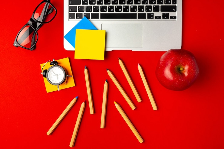 Foto vista superior del espacio de trabajo del estudiante con computadora portátil abierta y manzana roja, otros suministros, endecha plana