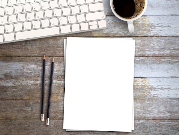 Vista superior Espacio de trabajo mínimo con papel blanco de teclado y taza de café sobre fondo de mesa de madera