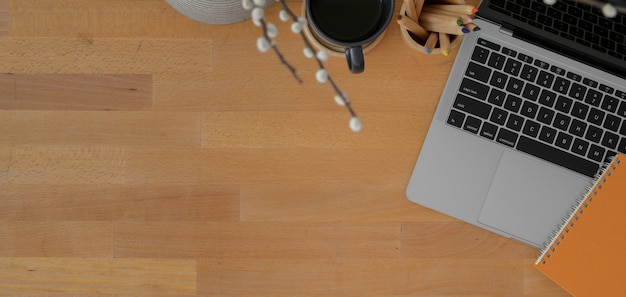 Vista superior del espacio de trabajo moderno con computadora portátil y suministros de oficina en mesa de madera