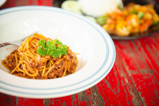 Vista superior de espaguetis con salsa de tomate y chuleta de cerdo en mesa de madera