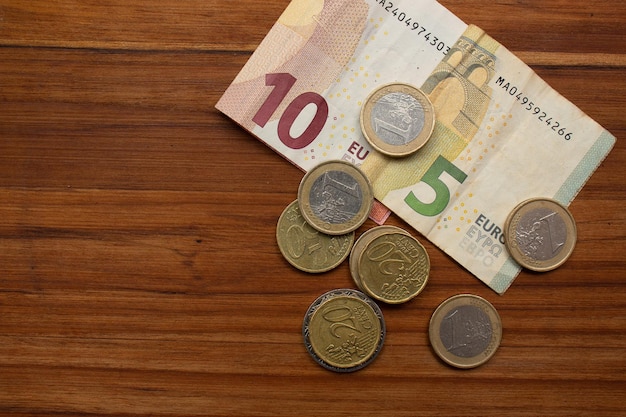 Vista superior de euros y varias monedas en una mesa de madera.