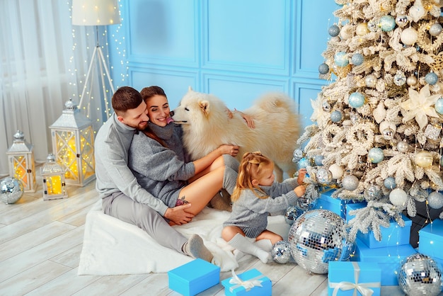 Vista superior de la familia feliz mamá papá hija y perro que pasan tiempo juntos cerca del árbol de Navidad