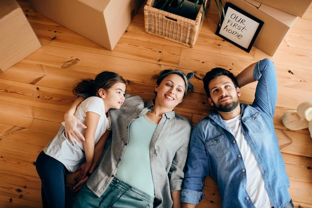 Vista superior de una familia feliz relajándose en el suelo en su nuevo hogar