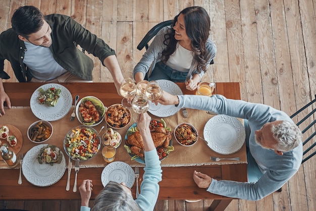 Foto vista superior de la familia multigeneracional brindando mientras cenan juntos