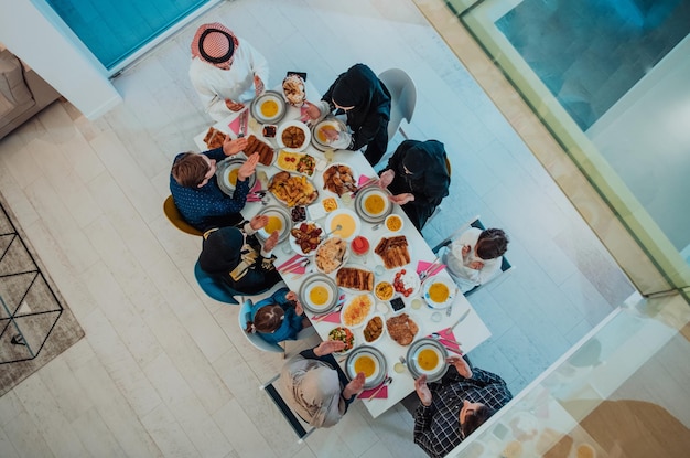 Vista superior de la familia musulmana cenando Iftar bebiendo agua para romper la fiesta. Comer comida tradicional durante el mes de fiesta del Ramadán en casa. La comida y bebida halal islámica en el hogar moderno.