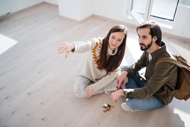 Vista superior de la feliz pareja joven con llaves en nuevo piso, nuevo hogar y concepto de reubicación.