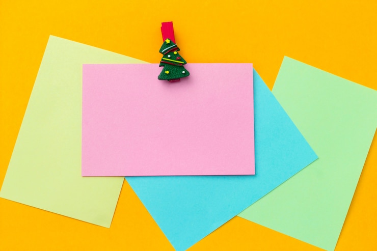 Foto vista superior festiva pinza para la ropa de navidad y hojas de papel vacías con espacio libre para texto sobre un fondo amarillo vibrante