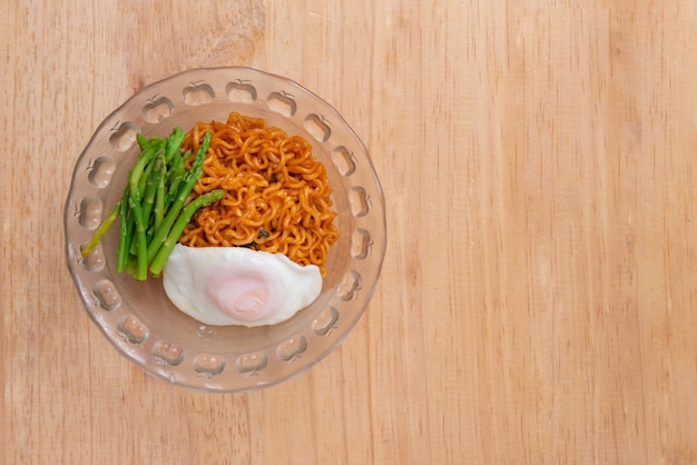 Vista superior de fideos con huevo y espárragos sobre fondo de mesa de madera con espacio de copia