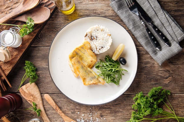 Vista superior de filete de pescado blanco asado con arroz y rúcula