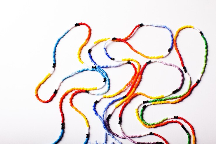 Foto vista superior flatlay pequeñas cuentas de colores ensartadas en una cuerda creando una cadena larga fondo blanco concepto de diversidad