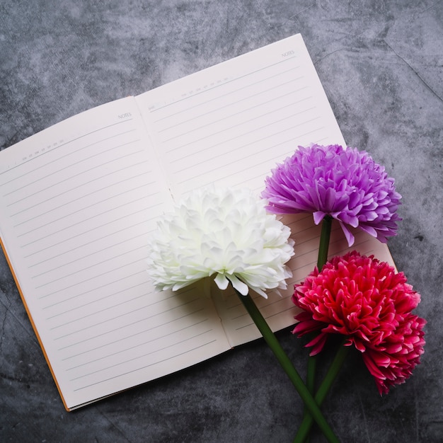 Vista superior de flores de crisantemo artificiales en una sola línea de cuaderno