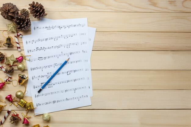 Vista superior folha de música papel de nota e decoração de natal em fundo de madeira