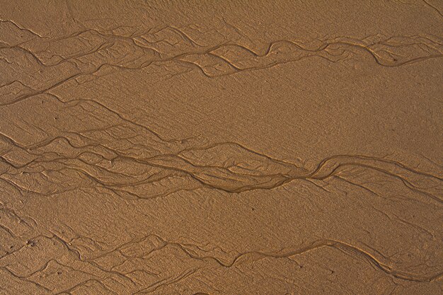 Vista superior del fondo de líneas con textura en la arena en la playa creada por la marea baja.