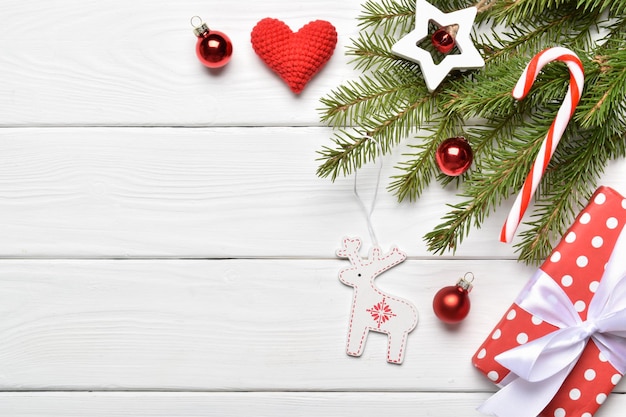 Vista superior de un fondo de ramas de abeto, adornos navideños y regalos en una mesa de madera blanca. Tarjeta de felicitación de año nuevo. Una maqueta de un saludo navideño. Un lugar para copiar. Endecha plana.