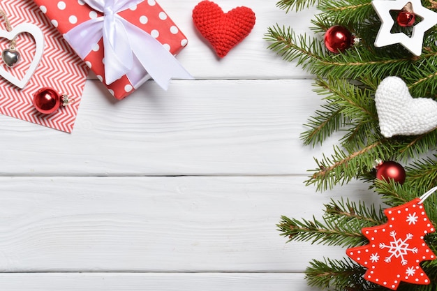 Vista superior de un fondo de ramas de abeto, adornos navideños y regalos en una mesa de madera blanca. Tarjeta de felicitación de año nuevo. Una maqueta de un saludo navideño. Un lugar para copiar. Endecha plana.