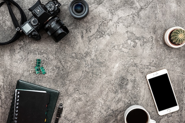 Vista superior de un fondo de yeso con una cámara fotográfica, teléfono inteligente y papelería