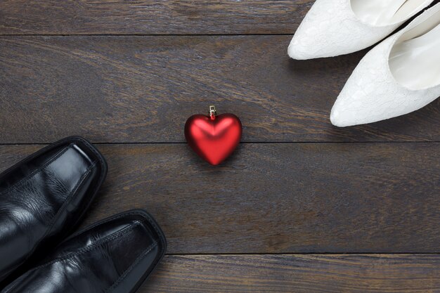 Vista superior forma de corazón con los zapatos de los hombres y los zapatos de las mujeres sobre fondo de madera.