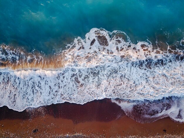 Vista superior de la foto del avión no tripulado volador de coral exótico paisaje marino con aguas turquesas y olas que se acercan a la playa de grava.