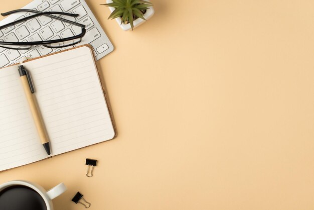 Vista superior de la foto de gafas en carpetas de bolígrafos de planificador de maceta de teclado blanco y taza de café sobre fondo beige aislado con copyspace