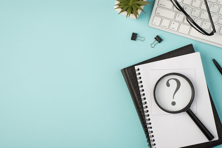 Foto vista superior de la foto de la pegatina de los blocs de notas con marca de interrogación, lupa, carpetas de vidrio, pluma, gafas de planta y teclado sobre fondo azul pastel aislado con espacio de copia