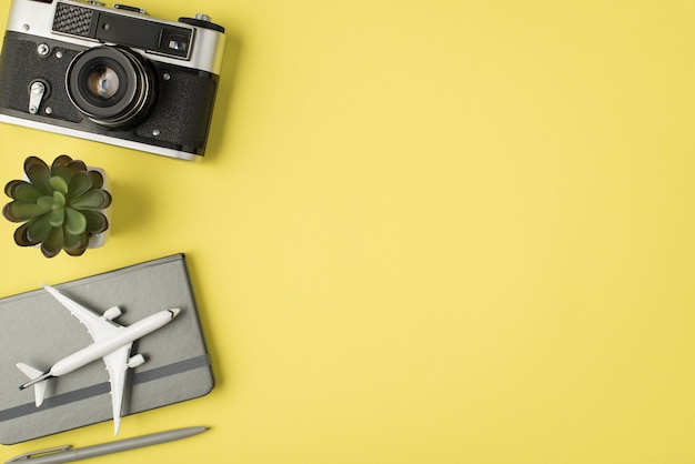 Vista superior de la foto de la pluma de la maceta de la cámara y el modelo de avión en el planificador gris sobre fondo amarillo pastel aislado con espacio de copia