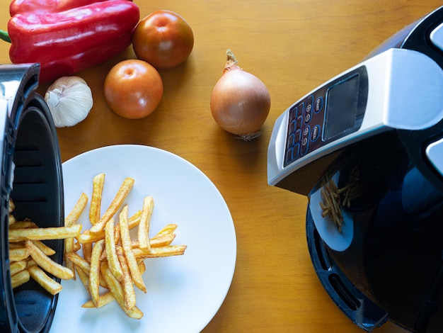 Vista superior de una freidora con un plato de papas fritas y verduras Concepto de comida saludable