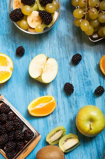 Vista superior de frutas y barries sobre un escritorio azul en estudio. Refresco natural nutrición tropical